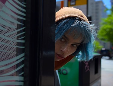 A blue-haired Zoë Kravitz peeking around a corner