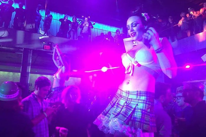 Image of woman in nightclub-like setting wearing white bra top and short green miniskirt dancing on ...