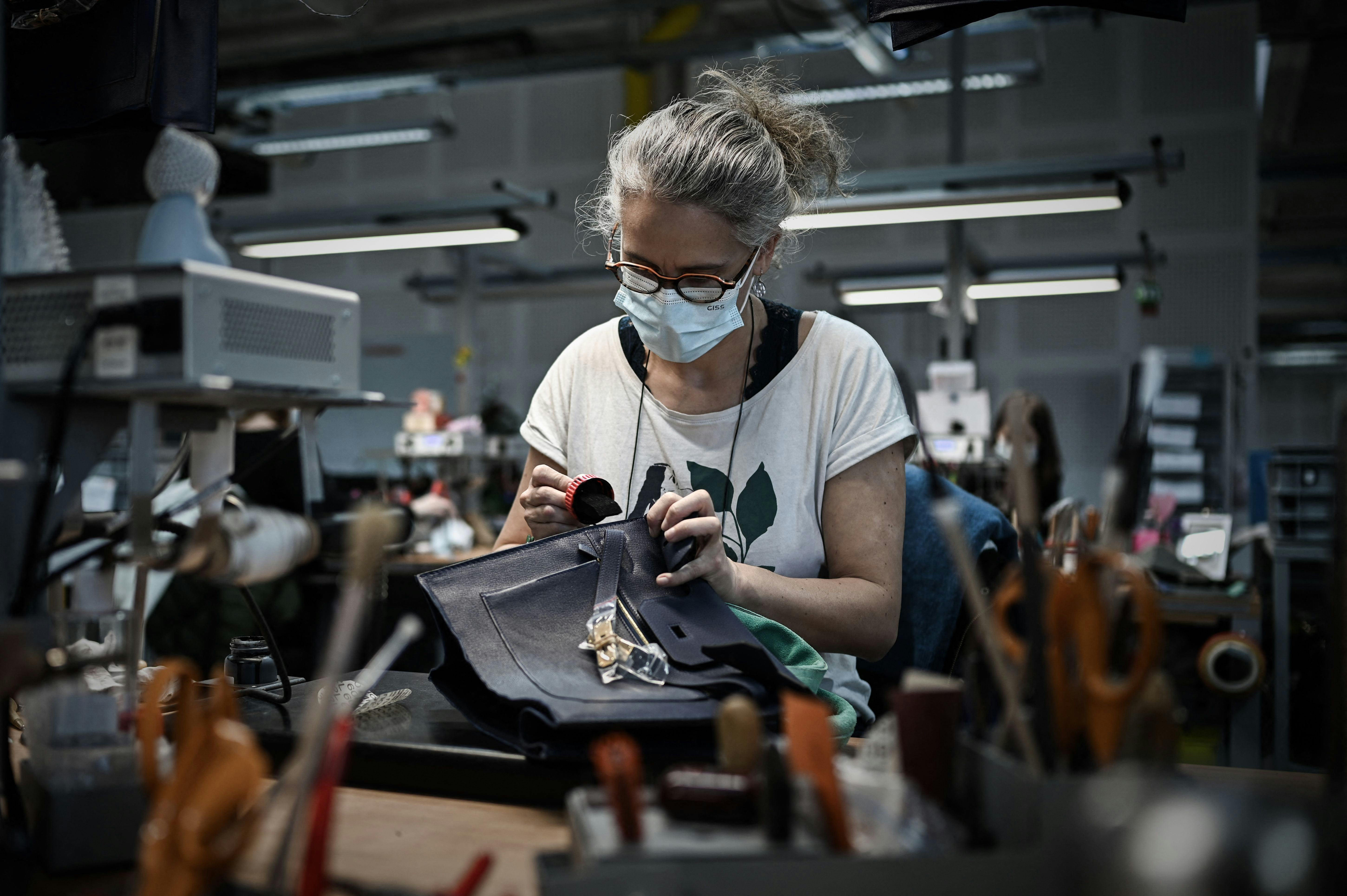 This picture taken on Jan. 6, 2022 shows an employee working on a leather handbag at the leather goo...
