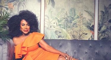 Sheryl lee ralph wearing an orange dress, seated on a couch