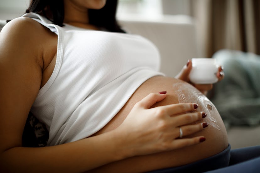 pregnant woman putting lotion on stomach