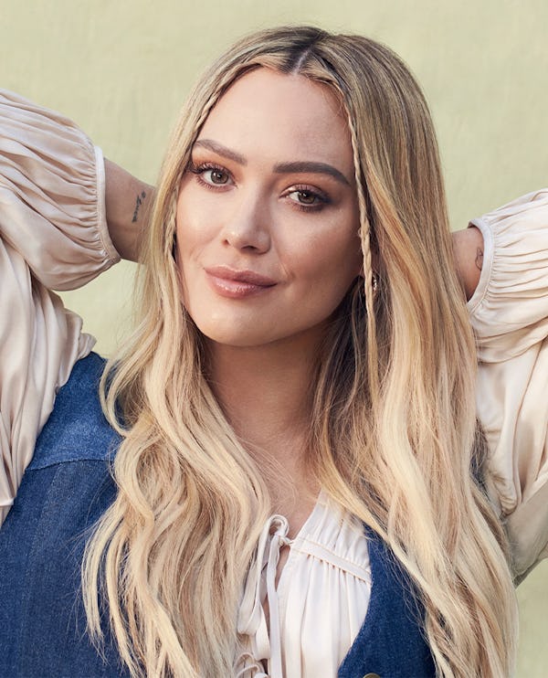 Hilary Duff crouching in a white Tove top and Coach vest