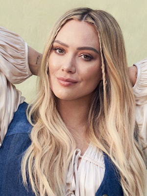 Hilary Duff crouching in a white Tove top and Coach vest