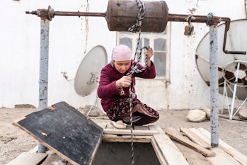 Tasikhan Tilebaldieva draws water from the well in Tajikistan