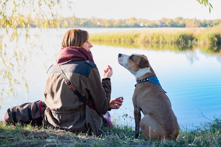 woman and a dog sitting by a lake