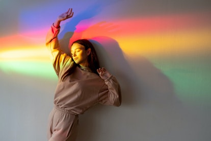 Young woman basking in rainbow colored light, thinking about the fact that February 2022 will be the...