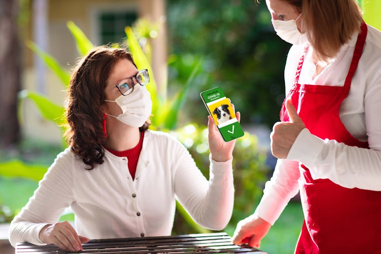 Customer holding phone with dog photo on it to restaurant worker.