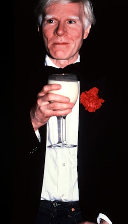 Andy Warhol holding a wine glass of milk