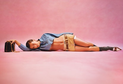 Hailey Bieber in a belted, low slung mini skirt and cropped blouse as part of Miu Miu's Spring/Summe...
