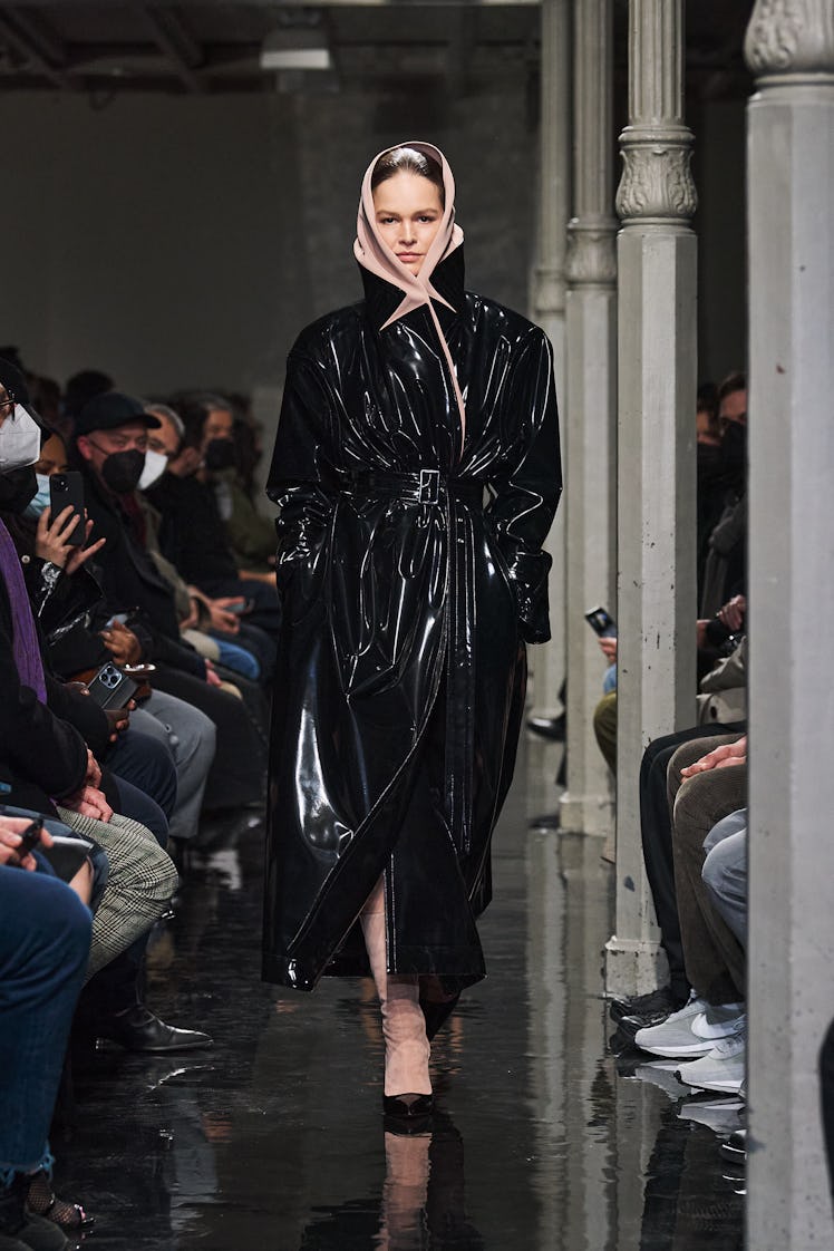 Model wears black trench and head scarf on Alaïa fall 2022 runway.
