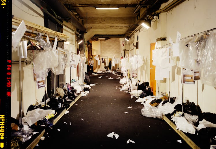 a messy backstage area with empty clothing racks