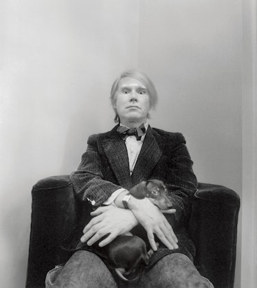 American pop artist Andy Warhol holding his dachshund dog friend, Archie, while wearing the Cartier ...