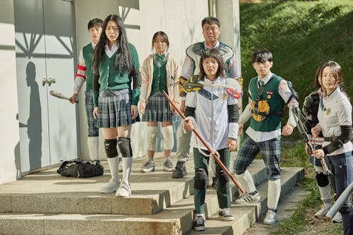 A screenshot from 'All of Us Are Dead' of a handful of students wearing school uniforms and using sc...