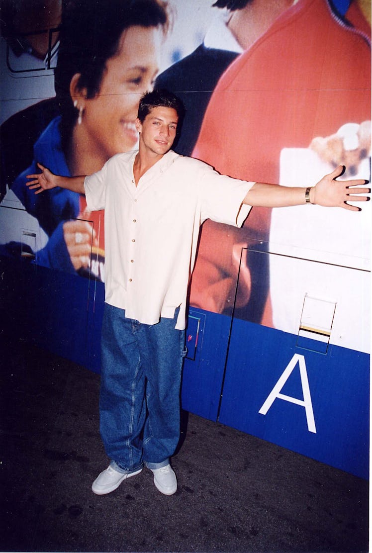 Simon Rex poses in an oversized outfit with arms wide open at the 1997 Tommy Hilfiger Party.
