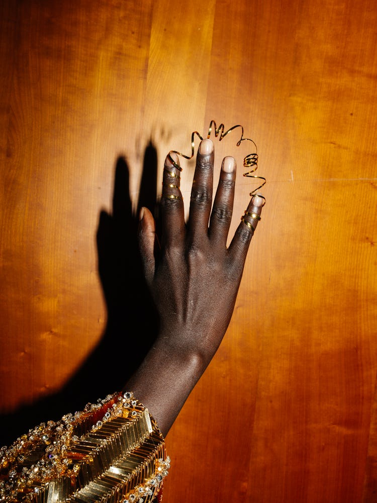 Fingers of a woman that is wearing a golden ring that connects two fingers