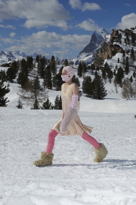 A campaign image of a model in the snow wearing fuzzy boots for Miu Miu. 