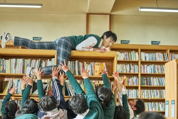 One student climbs a bookshelf to get away from zombies in All of Us Are Dead.