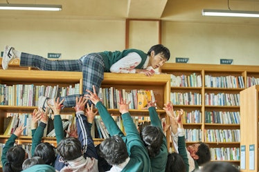 One student climbing a bookshelf to get away from zombies in All of Us Are Dead