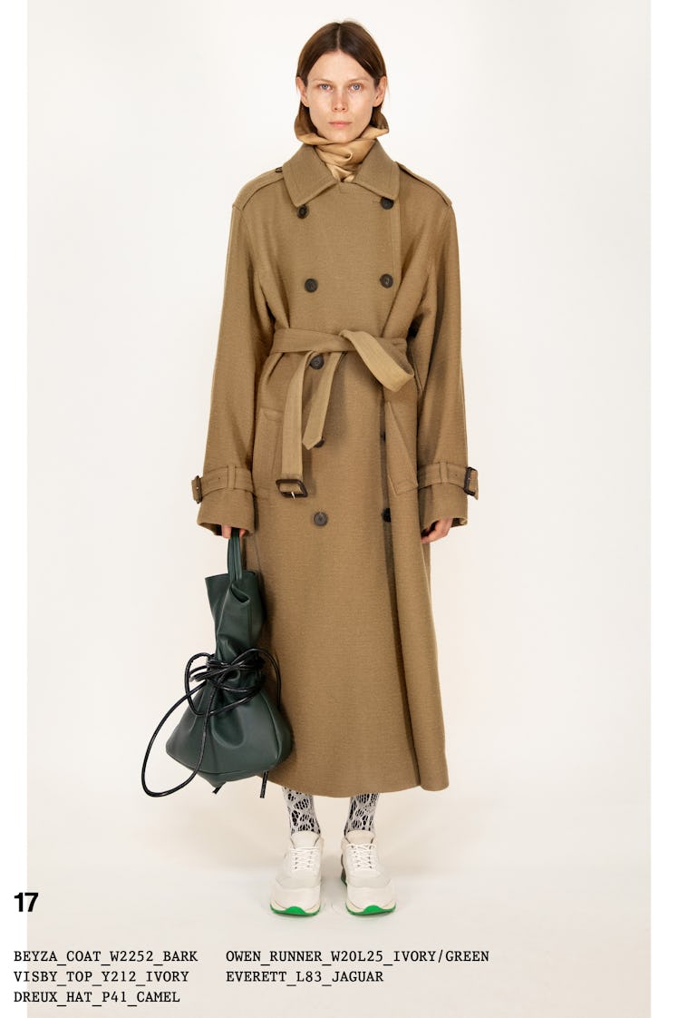 Model on the NY Fashion Week Fall 2022 in The Row light brown trench coat and a leather dark green p...