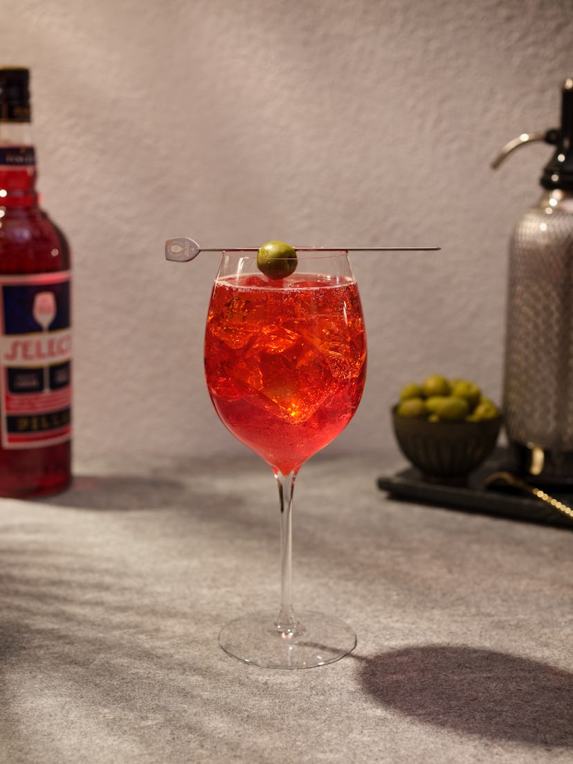 A glass with Select Spritz and a stick with an olive on top