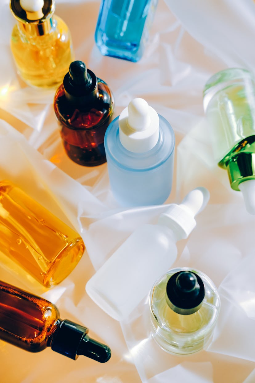 Various bottles in different colors containing serums and skincare products