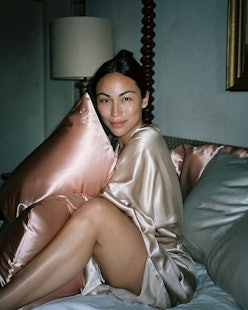 A girl in a sleeping dress hugging a pillow with a silk rose-gold pillowcase with beauty benefits