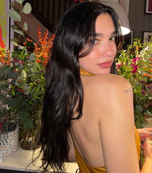 Dua Lipa looking over shoulder in gold top