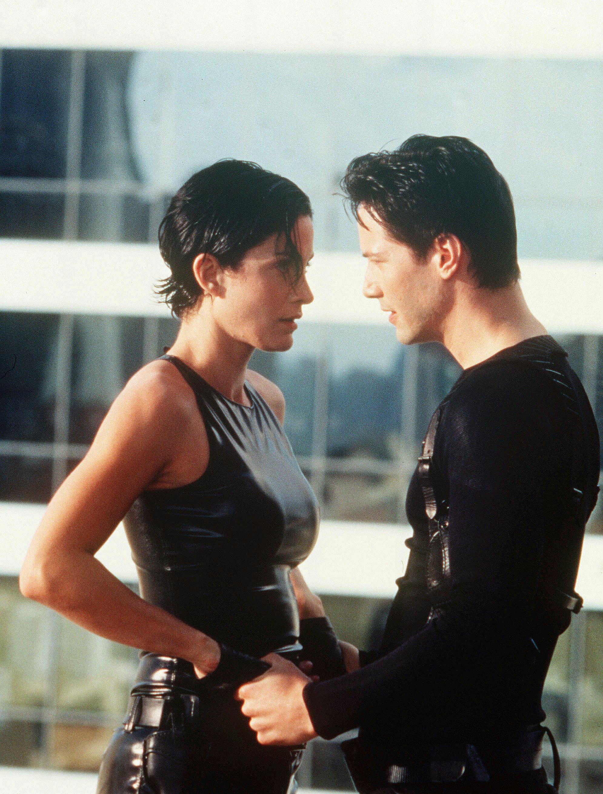 Carrie-Anne Moss in all-black latex and Keanu Reeves in all-black in "The Matrix"