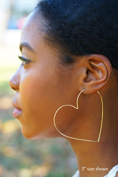 Woman modeling gold, large heart-shaped hoop earring