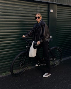 Claire Rose riding a bike with a white Prada handbag
