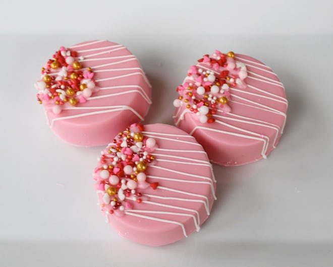 Three Oreos, dipped in pink chocolate and decorated with sprinkles