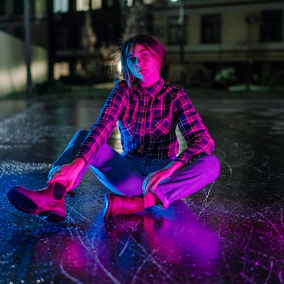 Young woman illuminated by blue and purple light during Mercury retrograde winter 2022, which will a...
