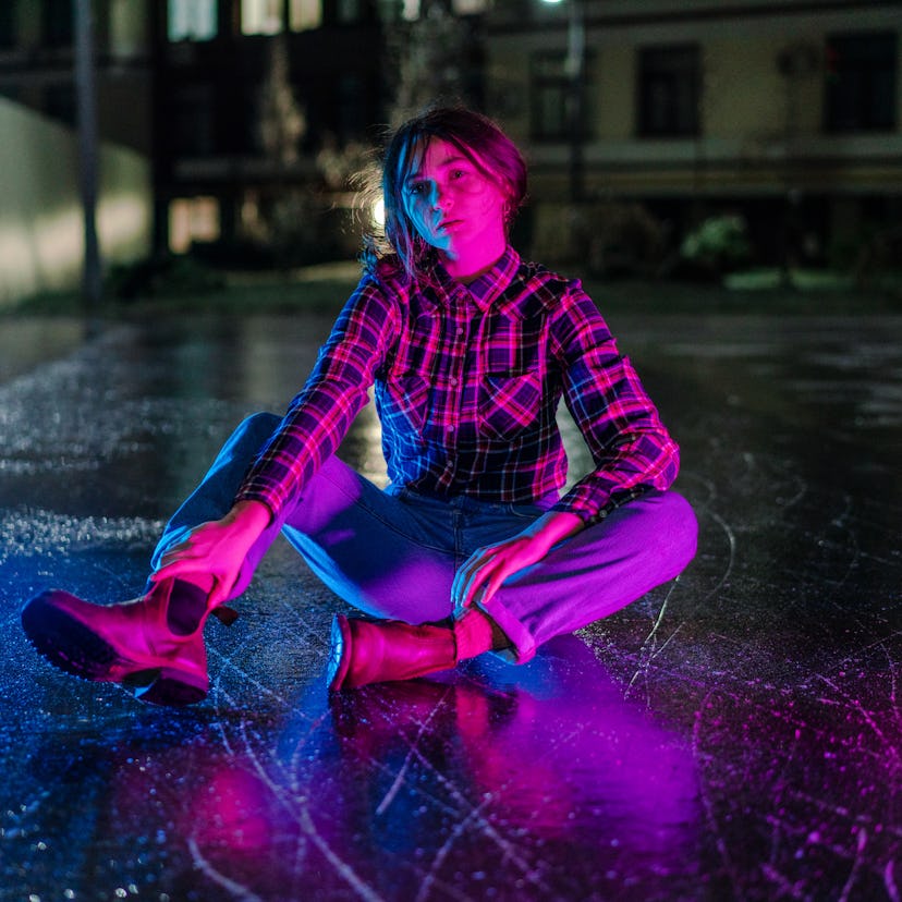 Young woman illuminated by blue and purple light during Mercury retrograde winter 2022, which will a...