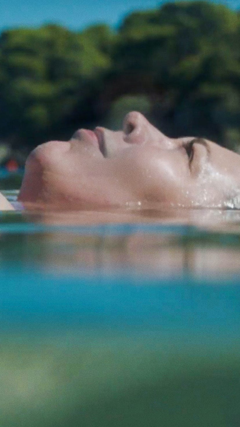 Olivia Colman as Leda floating in the water looking up at the sky 