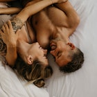 Man and woman laughing will holding each other in bed