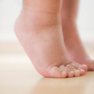 Close up of the feet of a toddler toe walking.