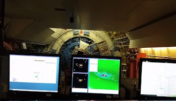 Photo of 3 computer screens in front of a bulkhead full of telescope hardware