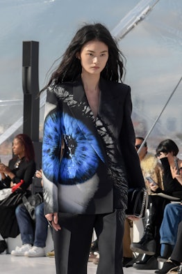 A model in a in a black suit with blue eye print at the Alexander McQueen spring 2023 fashion show