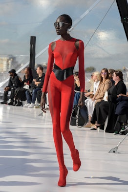 A model in a red jumpsuit and a black belt at the Alexander McQueen spring 2023 fashion show