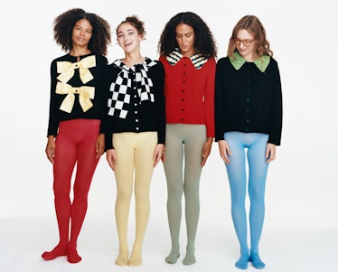 Four models standing side by side wearing colorful tights and cardigans covered with bows and bright...
