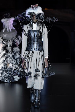 A model wearing a a grey checked suit-dress with a black corset and 3D floral elements by Noir Kei N...