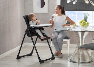 Woman Sitting At A Table With A Baby In A High Chair Next To Her
