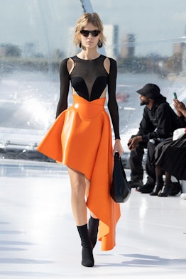 A model in a black top and an orange skirt at the Alexander McQueen spring 2023 fashion show