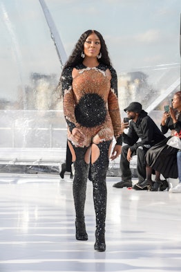 Naomi Campbell walking the runway at Alexander McQueen in a bedazzled catsuit in beige and black