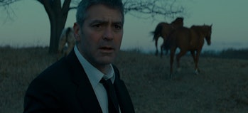 George Clooney stands several feet from a group of horses in Michael Clayton