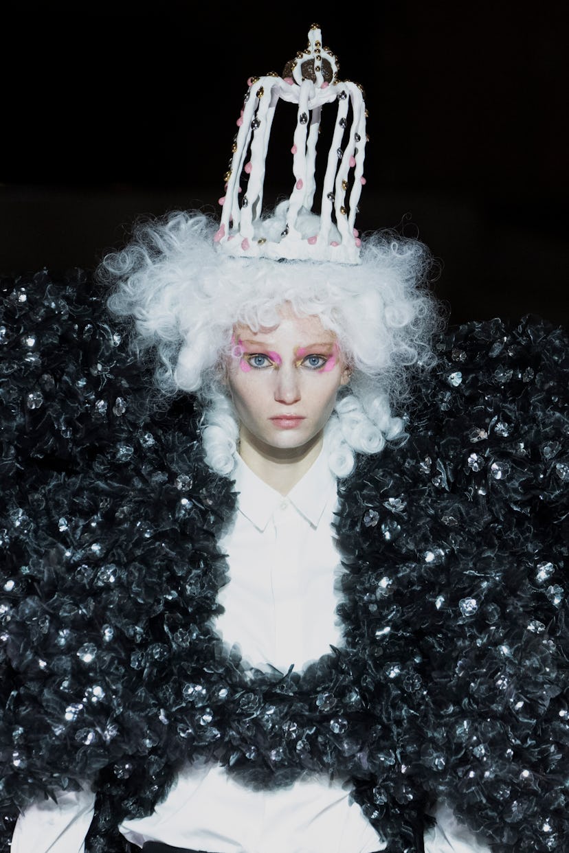A model wearing a large 3D print puffer jacket, a white with, and a white crown by Noir Kei Ninomiya
