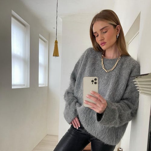 Rosie Huntington-Whiteley  taking a mirror selfie in a grey sweater and black leggings