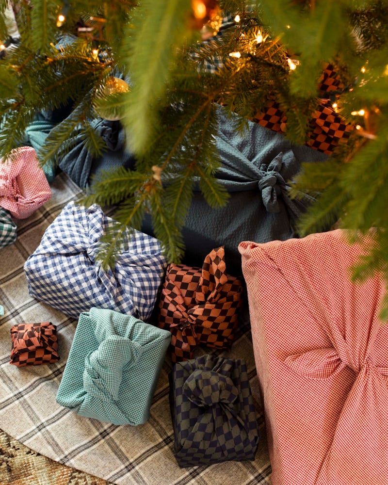 Various sized present boxes wrapped in fabric under Christmas tree placed by Amber Lewis