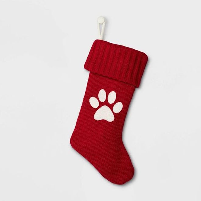 Red stocking with white paw print hanging on a white wall in an article about when does target put o...