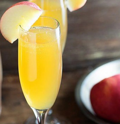 Apple Mimosa Cocktail in tall glasses and organic apples on wooden. Seasonal fall drinks for holiday...